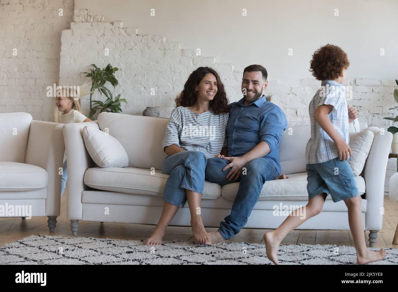 Happy parents watching two hyperactive energetic little sibling kids Stock Photo