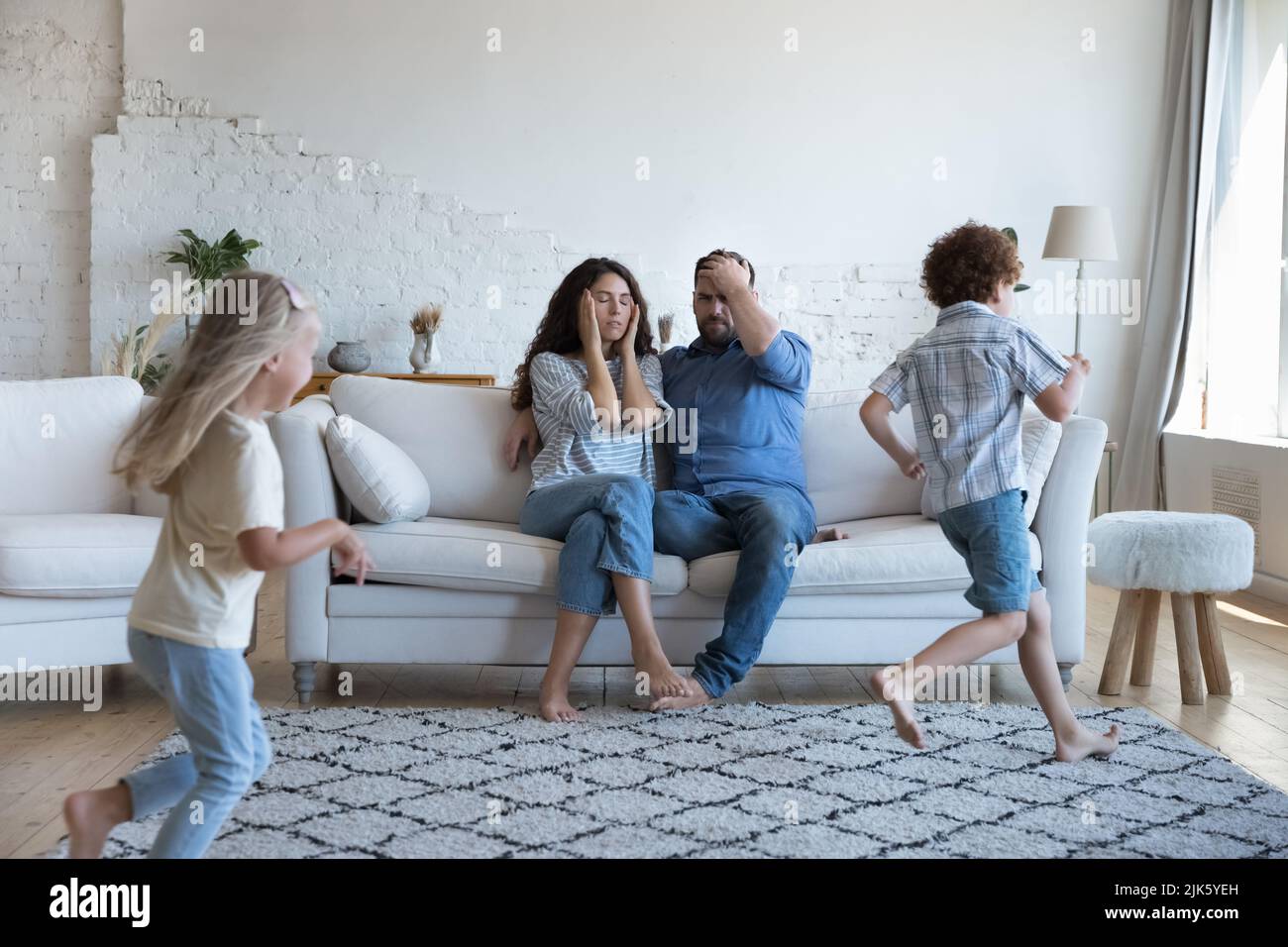 Two active kids running around tired parents, playing active games Stock Photo