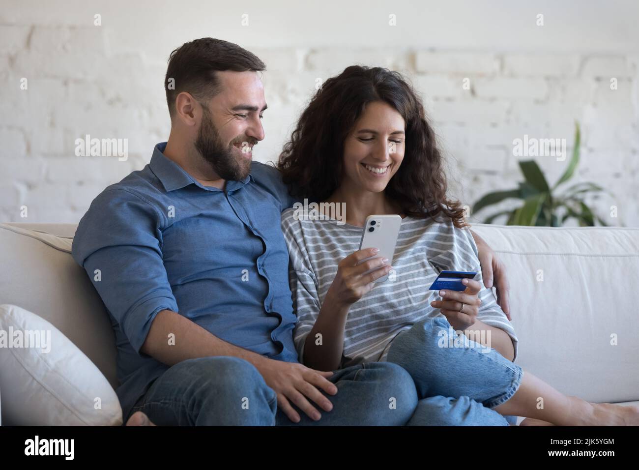 Cheerful couple holding cellphone and credit card, shopping online Stock Photo