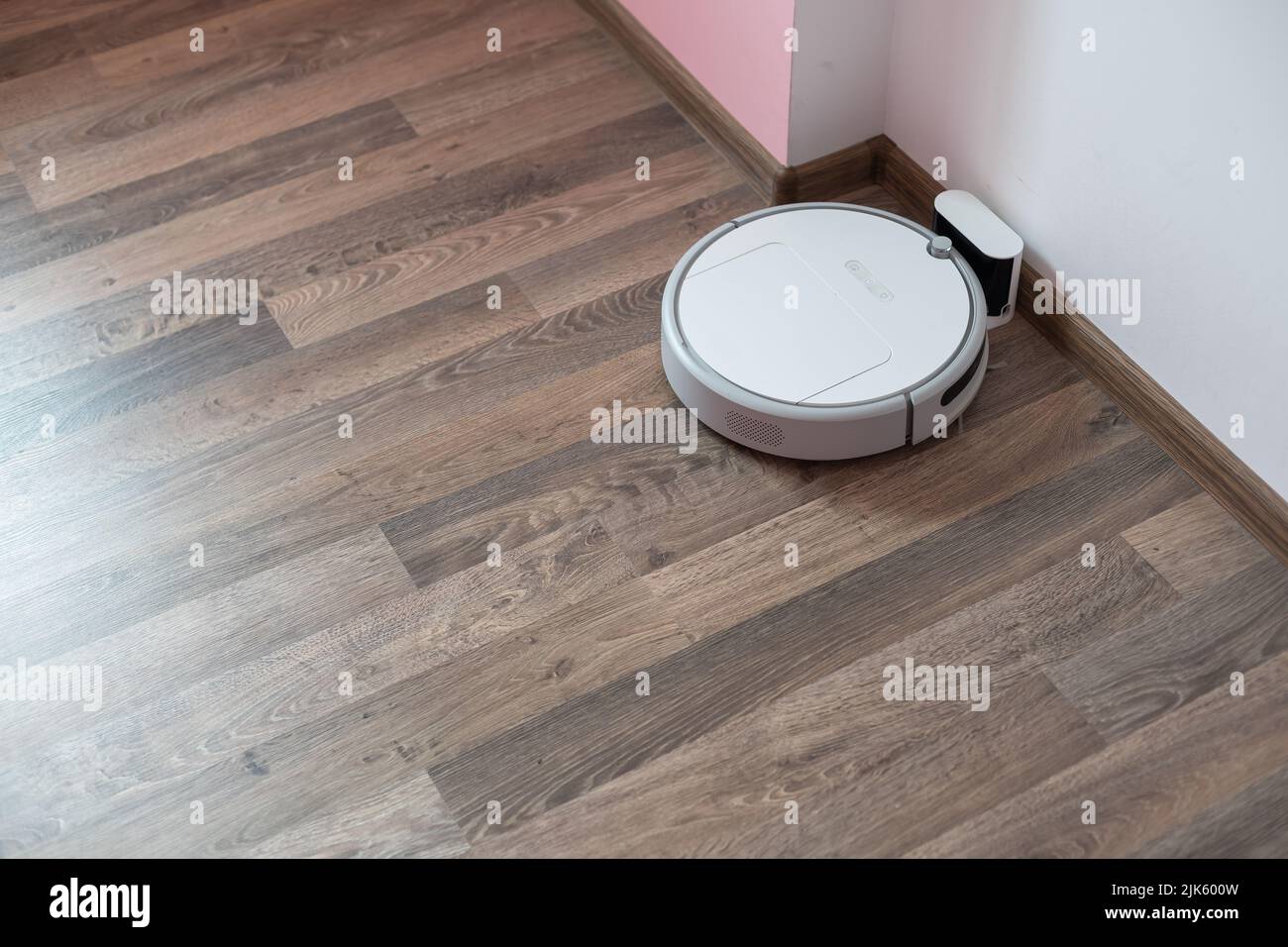 Robotic vacuum cleaner on laminate wood floor charging from base