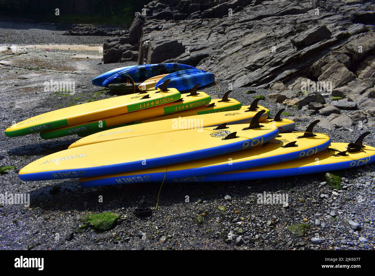 Yellow stand up paddle boards stacked on the beach, Stackpole Quay, Stackpole, Pembrokeshire, Wales Stock Photo