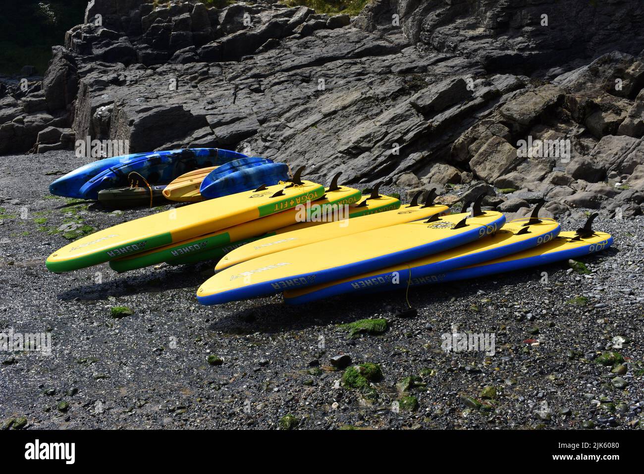 Yellow stand up paddle boards stacked on the beach, Stackpole Quay, Stackpole, Pembrokeshire, Wales Stock Photo