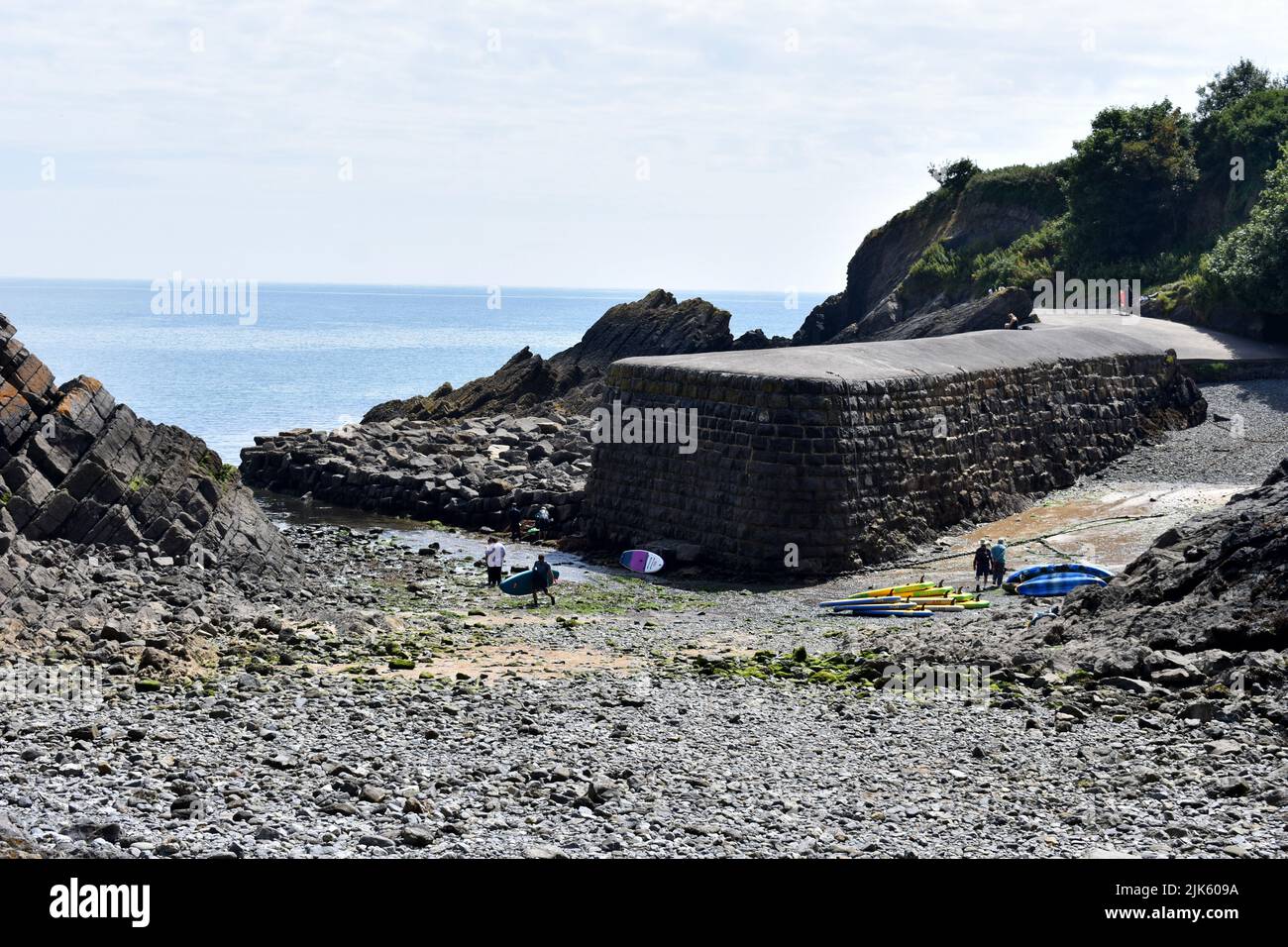 Paddle boarders getting ready at Stackpole Quay harbour at low tide, Stackpole, Pembrokeshire, Wales Stock Photo