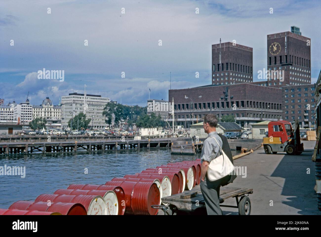 The waterfront and City Hall (right), Oslo, Norway in 1970. This modern, imposing red brick building looks out on the harbour in the Pipervika district of the capital city. Designed by Arnstein Arneberg and Magnus Poulsson, work started in 1931 but progress was halted by the outbreak of World War II.  It was finally inaugurated in 1950. The administrative seat of the City Council houses important murals and artworks from celebrated Norwegian painters and sculptors. Here, within its walls, the prestigious Nobel Peace Prize ceremony is held. This image is from an amateur 35mm colour transparency Stock Photo