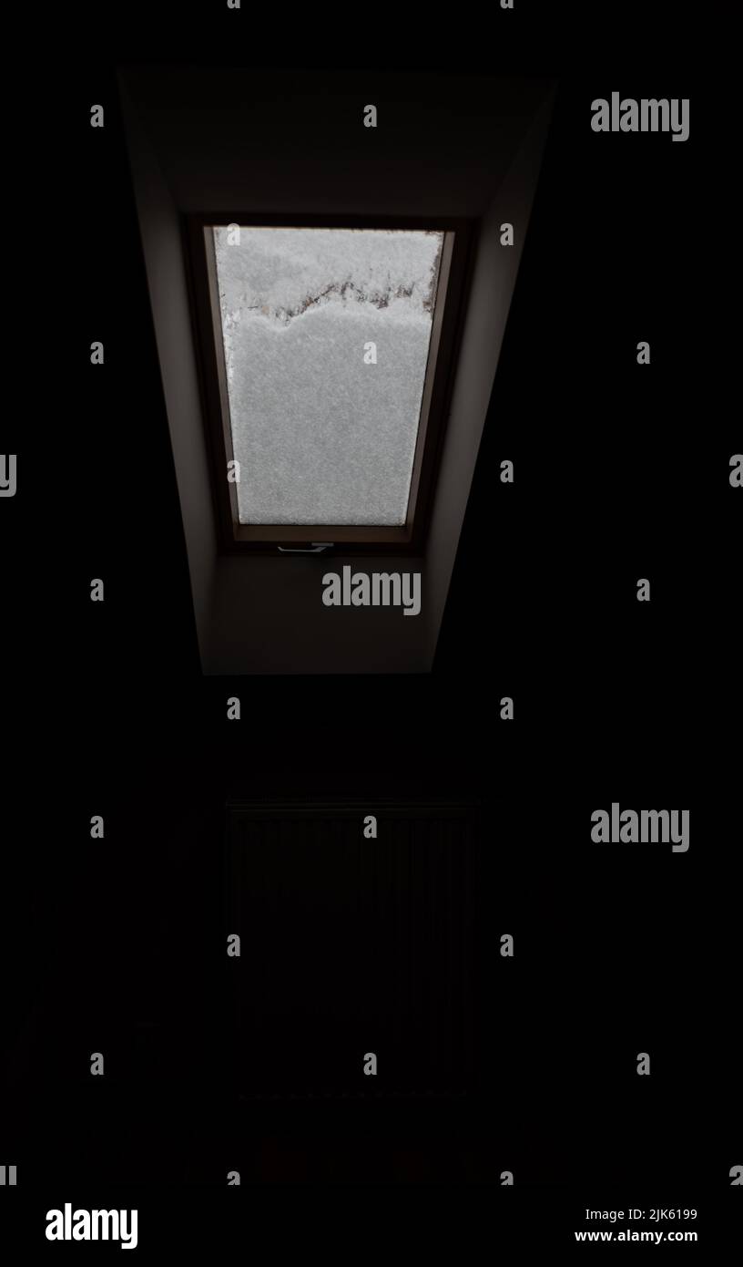 Roof window covered with snow. The snow on the glass blocks the light ...