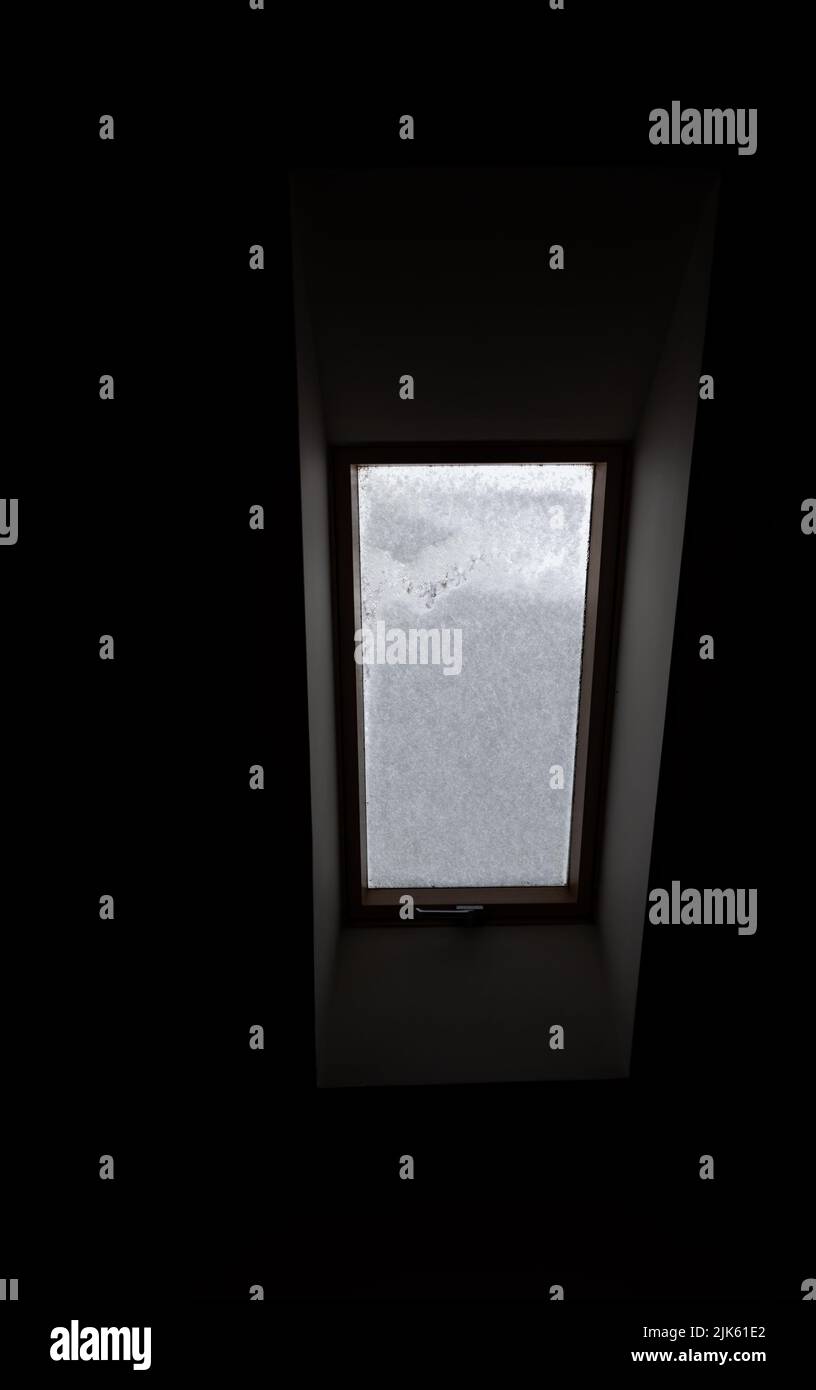 Roof window covered with snow. The snow on the glass blocks the light ...
