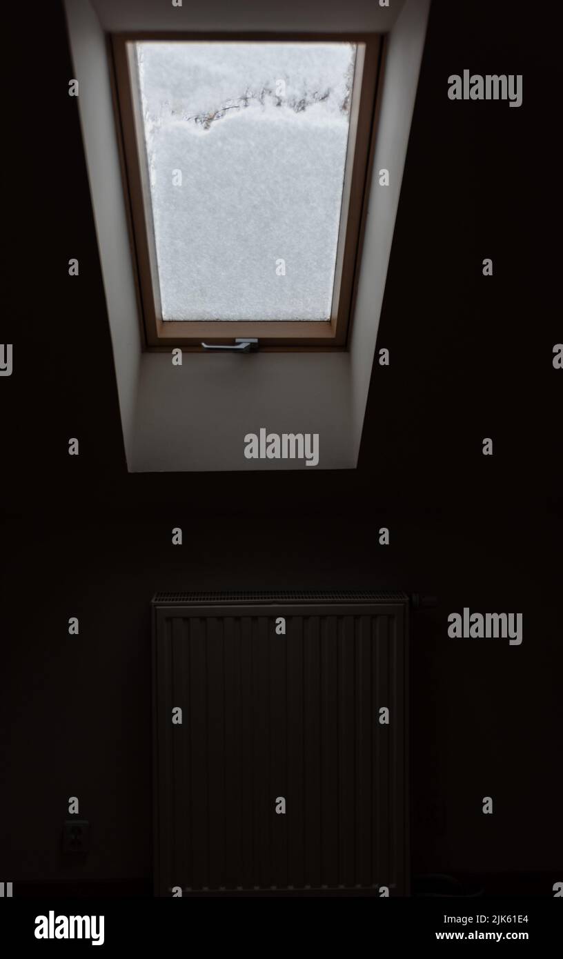 Roof window covered with snow. The snow on the glass blocks the light ...