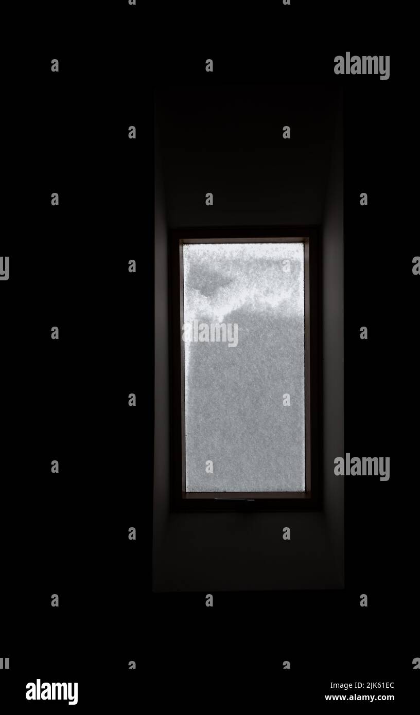 Roof window covered with snow. The snow on the glass blocks the light ...