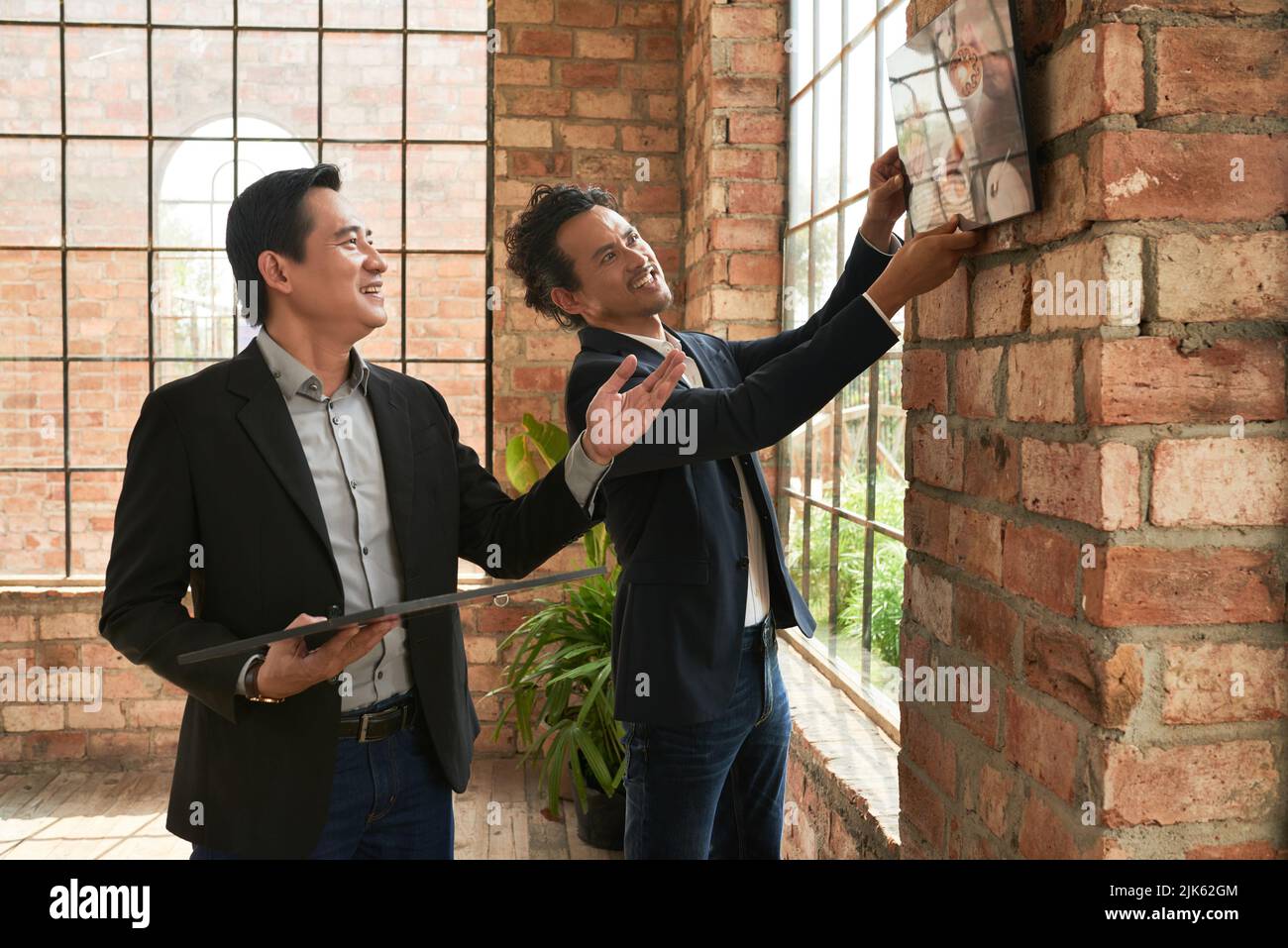 Entrepreneur hanging photos they have bought to open coffee shop Stock Photo