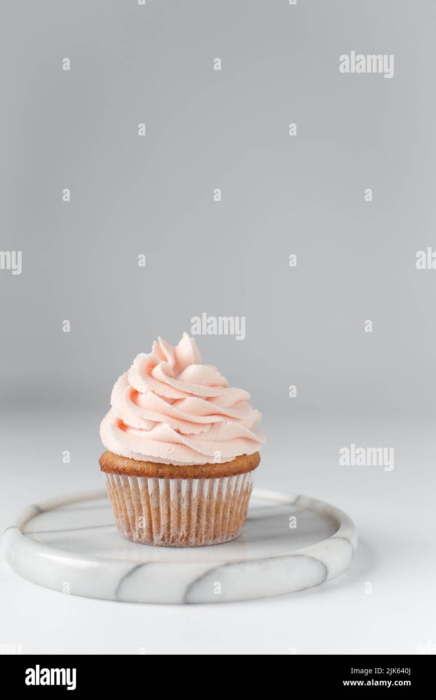 Vanilla cupcake with pink frosting, plain cupcake with pastel pink