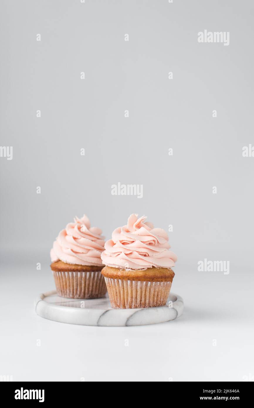 Vanilla cupcake with pink frosting, plain cupcake with pastel pink