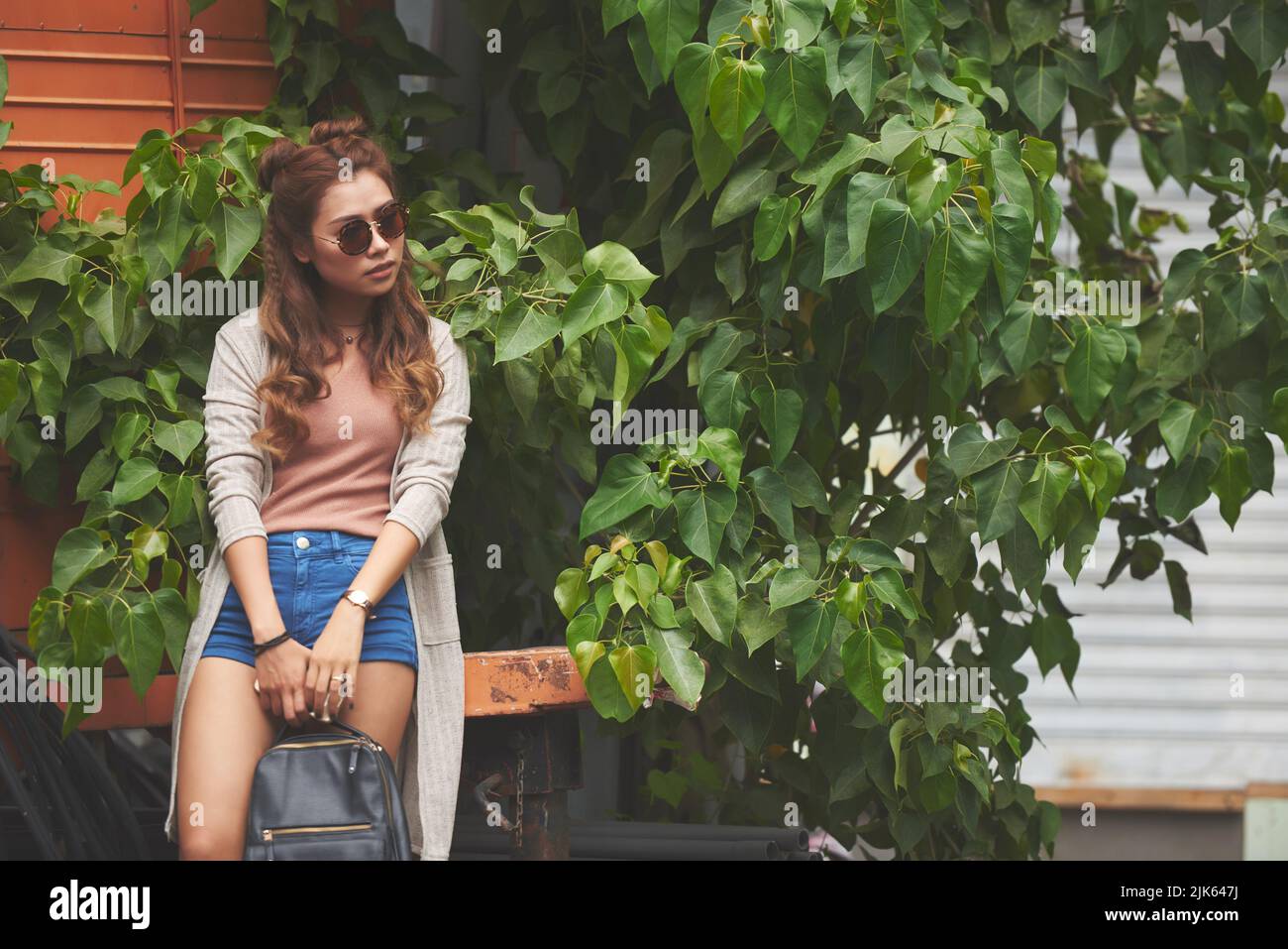 Beautiful Vietnamese young woman in sunglasses standing outdoors Stock