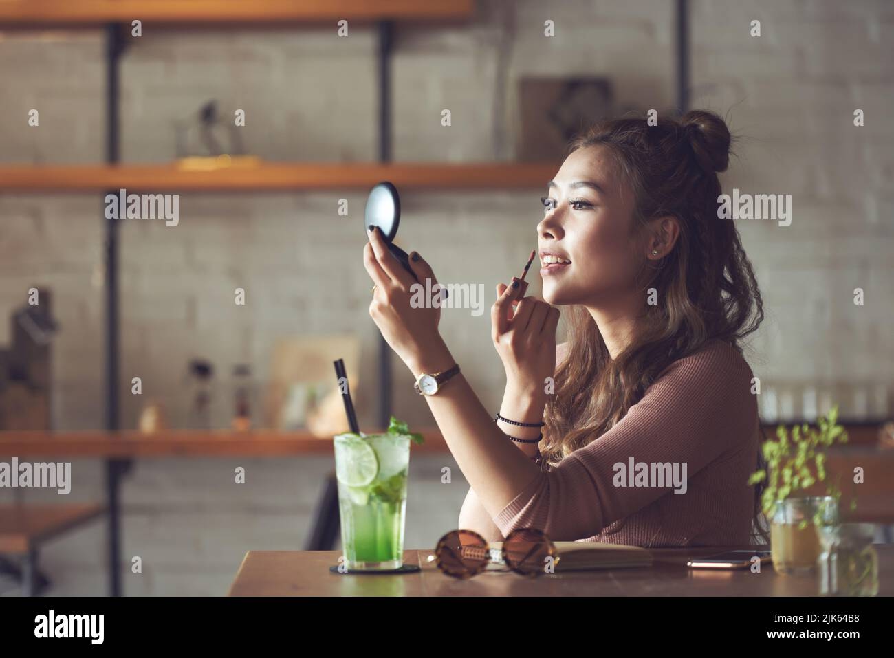 Beautiful Vietnamese young woman applying lip gloss Stock Photo