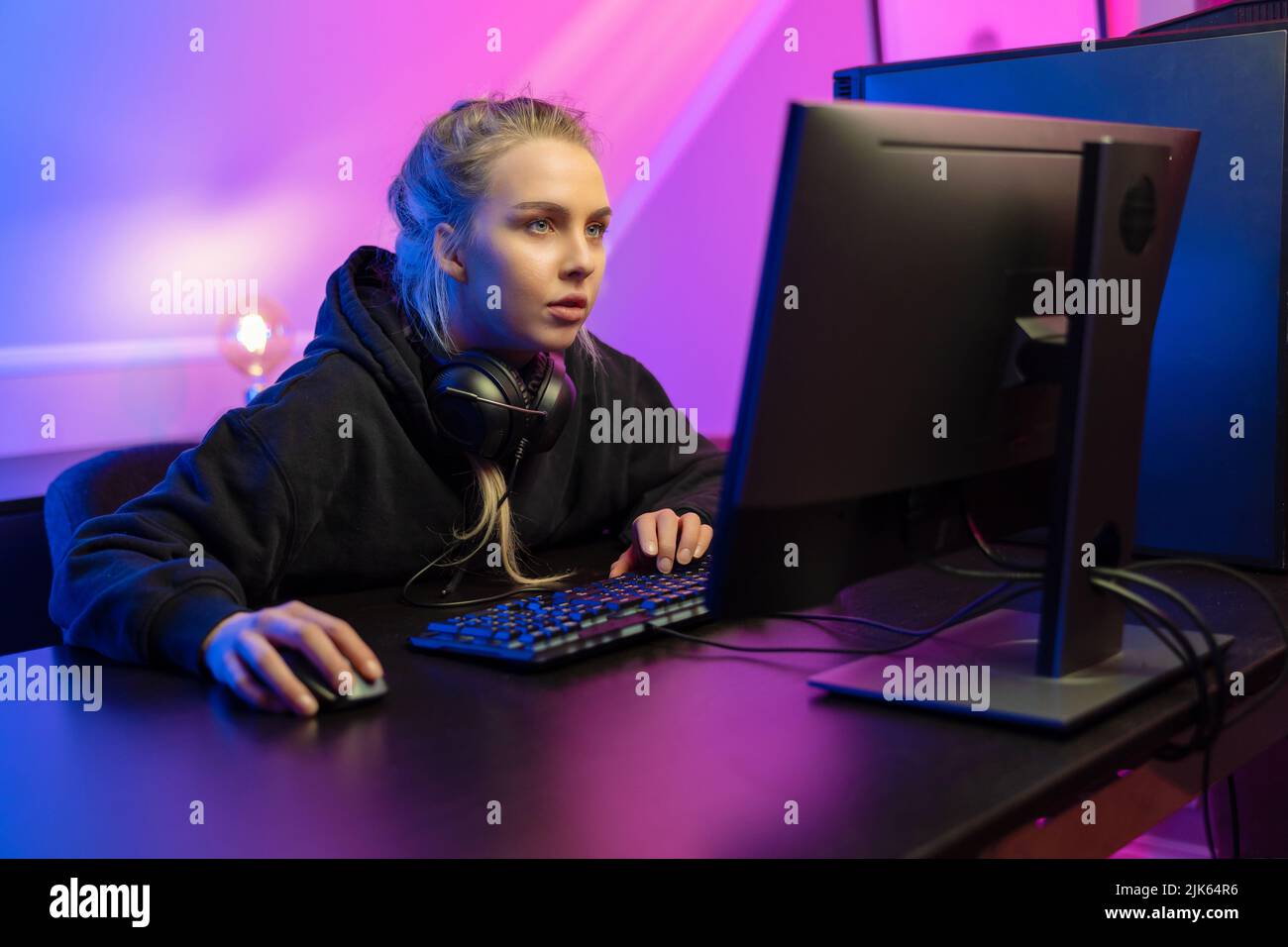 Focused Professional E-sport Gamer Girl in Hoody Playing Online Video Game on PC Stock Photo