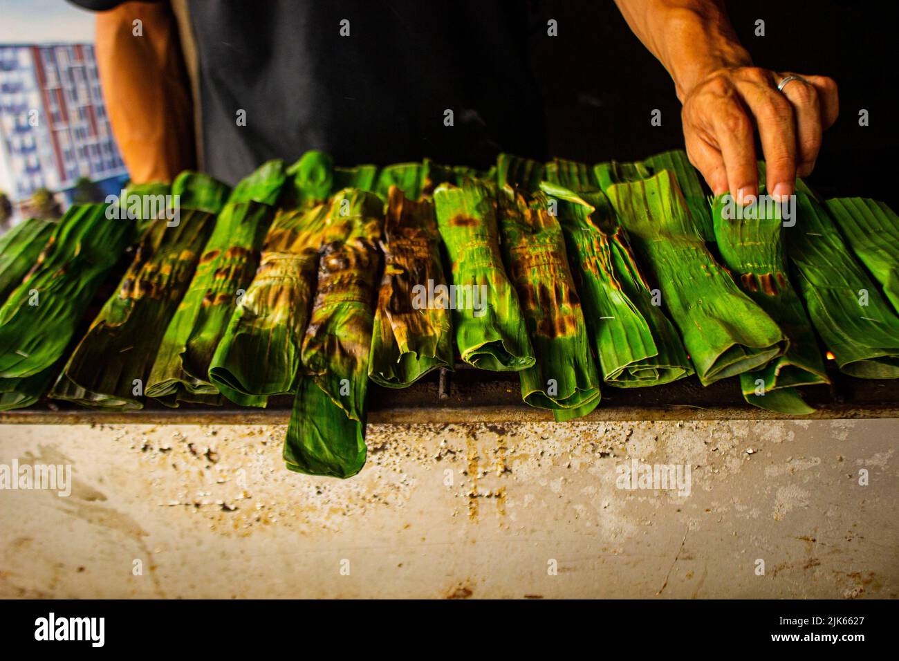 otak - otak is a food made from minced mackerel fish meat wrapped in banana leaves, baked, and served with spicy and sour sauce. otak-otak is traditio Stock Photo