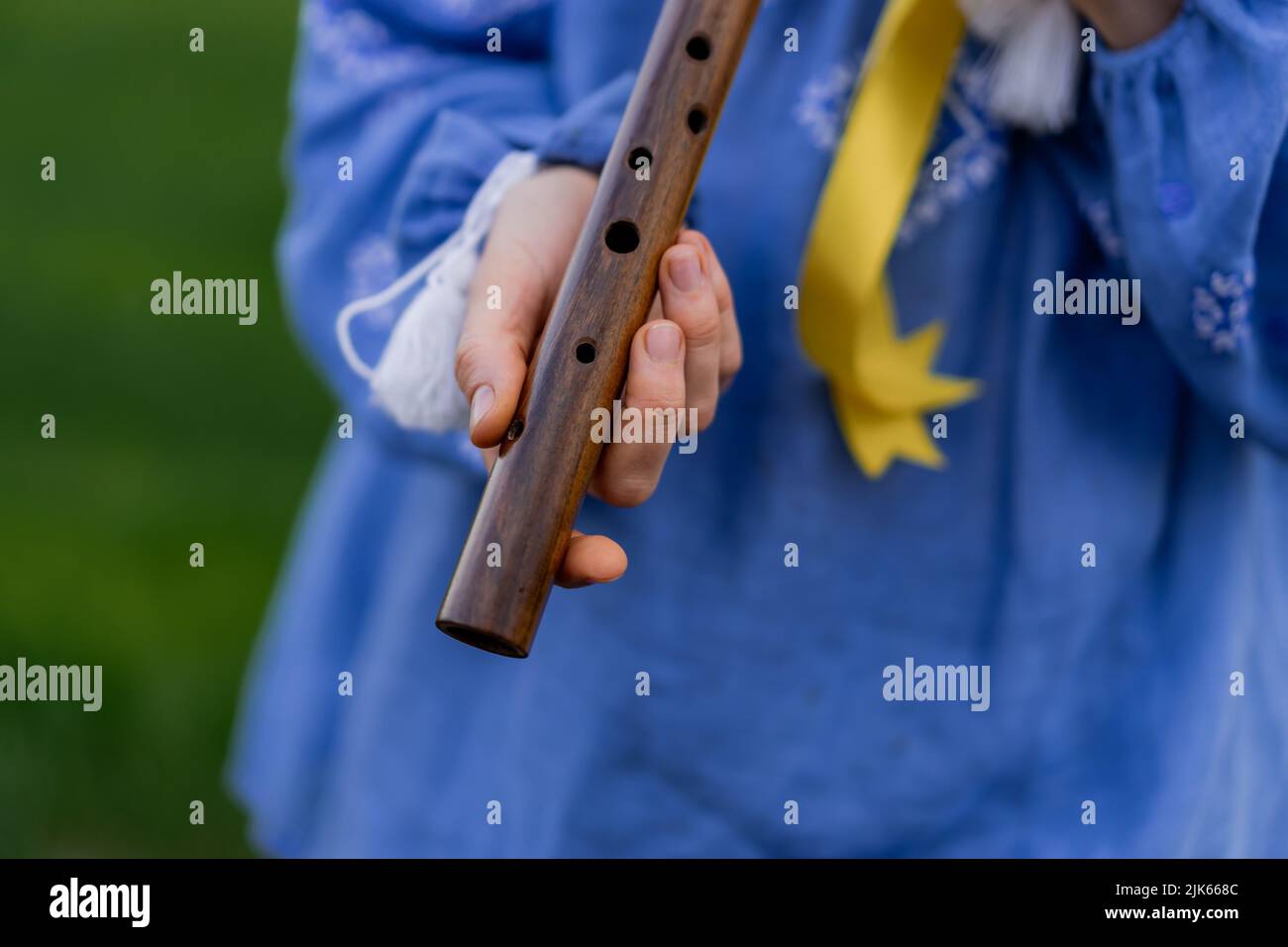 Woman playing woodwind wooden flute ukrainian sopilka outdoors. Folk
