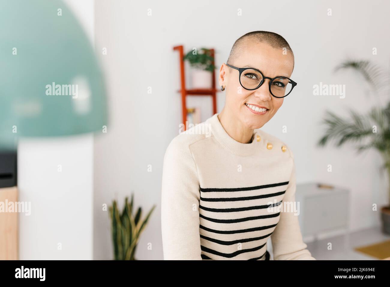 Successful mid adult business woman sitting on desk at home office Stock Photo