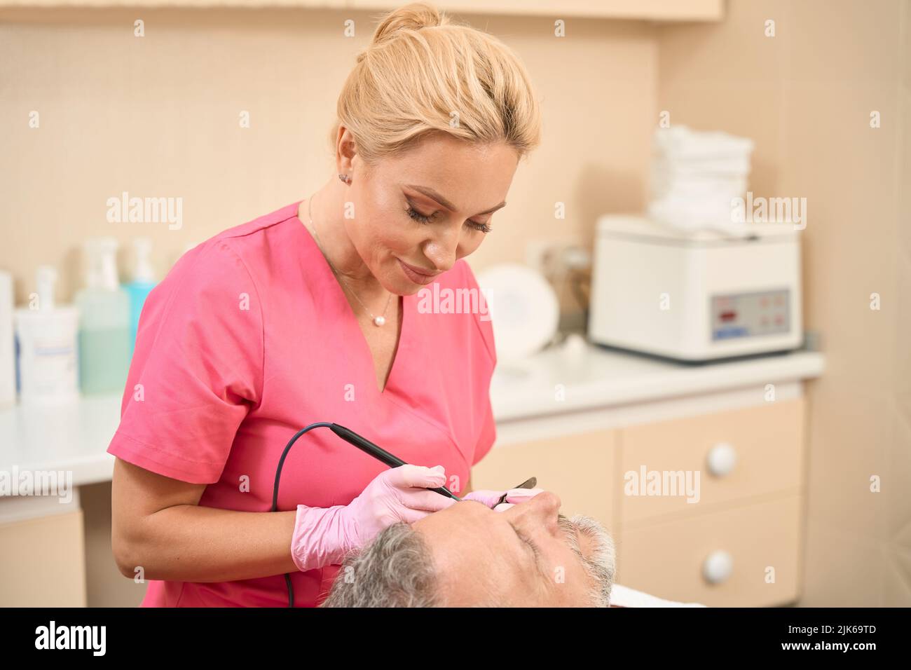 Smiling woman dermatologist surgeon removes neoplasm using radio wave