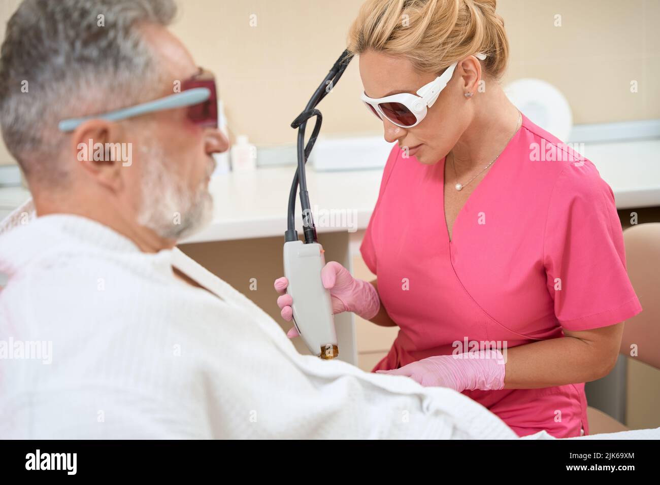 Woman dermatologist doing laser hair removal to man on arm Stock Photo