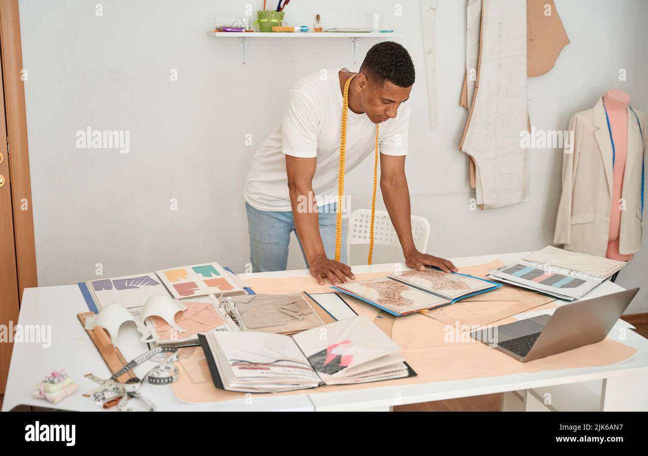 Young tailor working with drawings and laptop Stock Photo