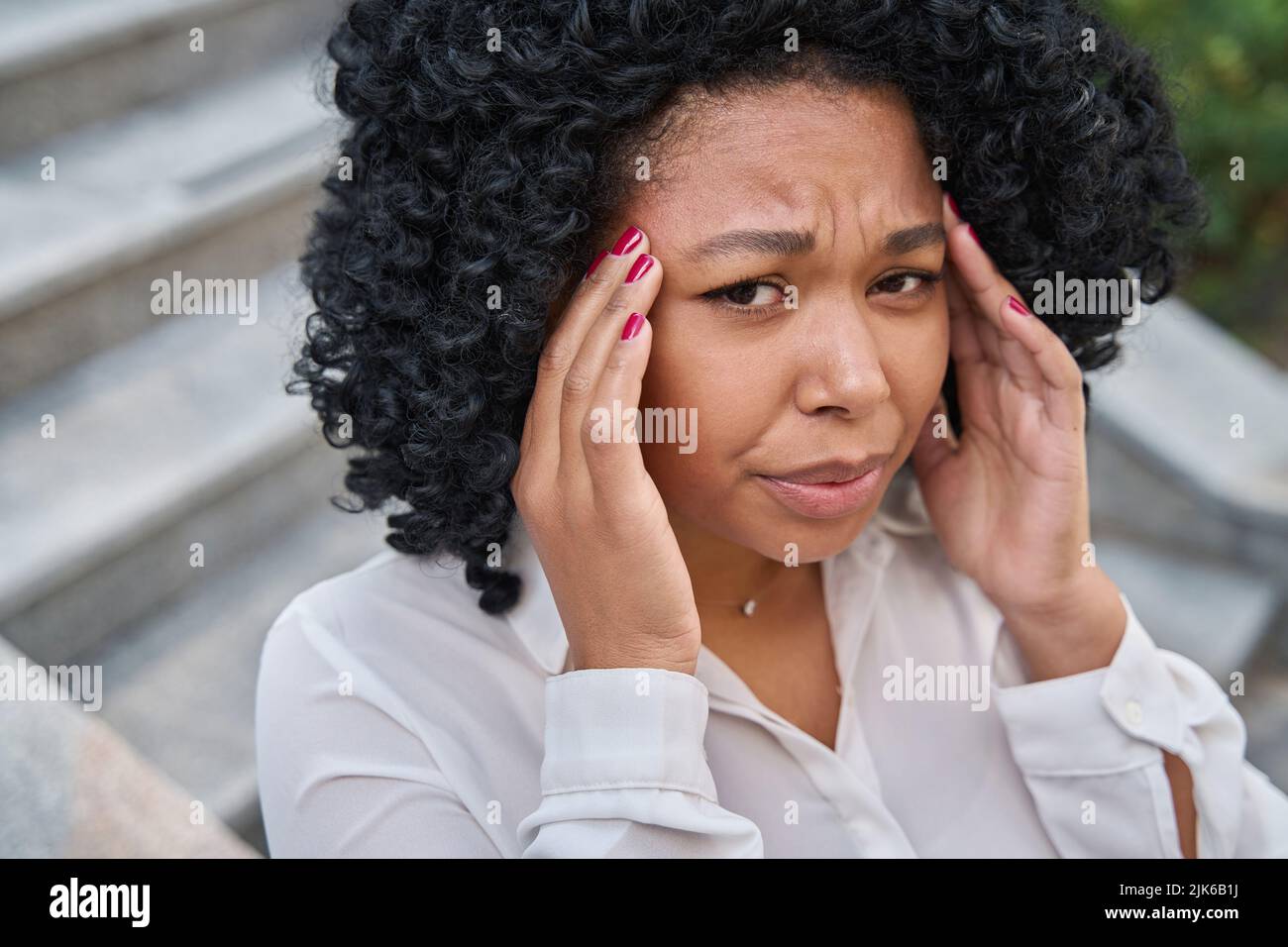 Woman clutches her temples and winces in pain Stock Photo Alamy