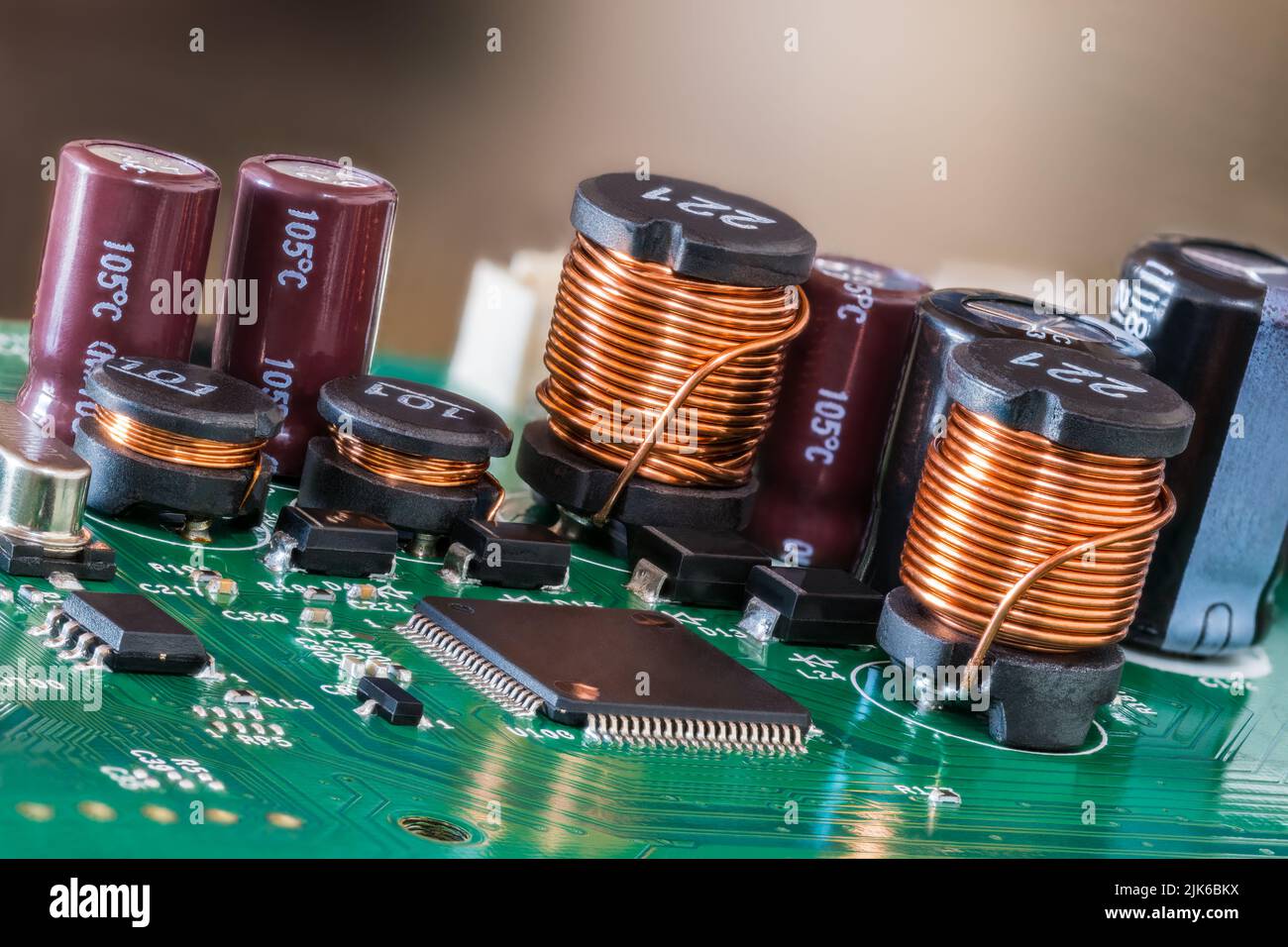 Closeup of electromagnetic coils and electrolytic capacitors or chips on green PCB. Various electrical components on printed circuit board. Inductors. Stock Photo