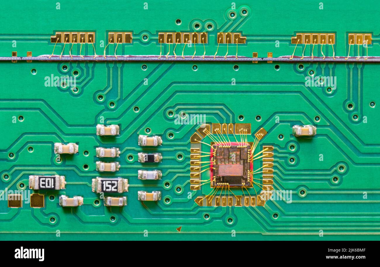 Integrated circuit die wired to green printed board texture with line scan camera. Close-up of chip bonded by gold wires to PCB inside flatbed scanner. Stock Photo