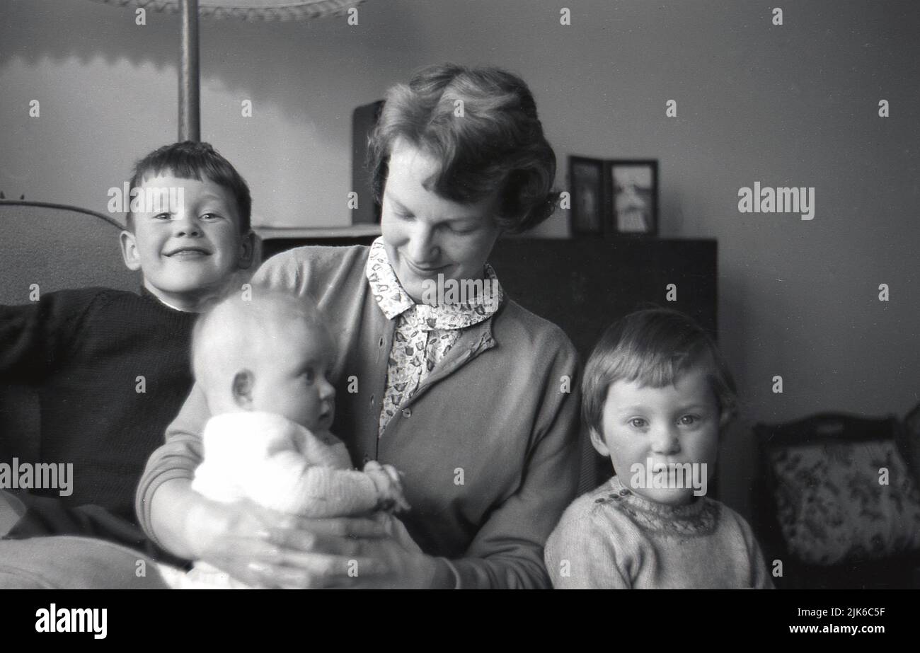 1960s, historical, a mother holding her baby, with her young son and daughter sitting with her for a family photo, England, UK. Stock Photo