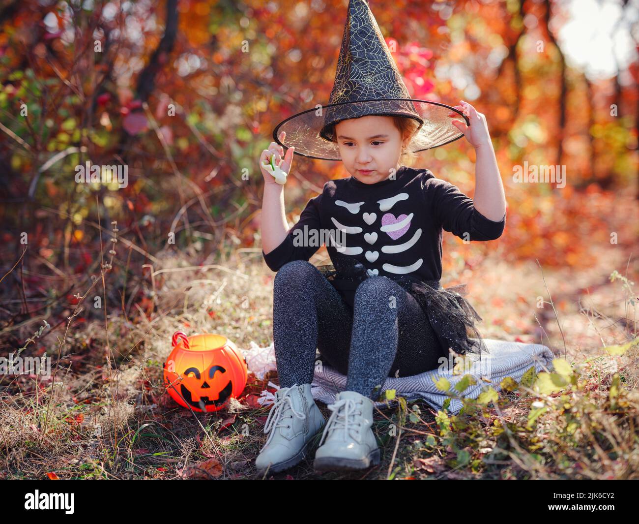 Young girl in black costume goes trick or treating. Little witch, Kids