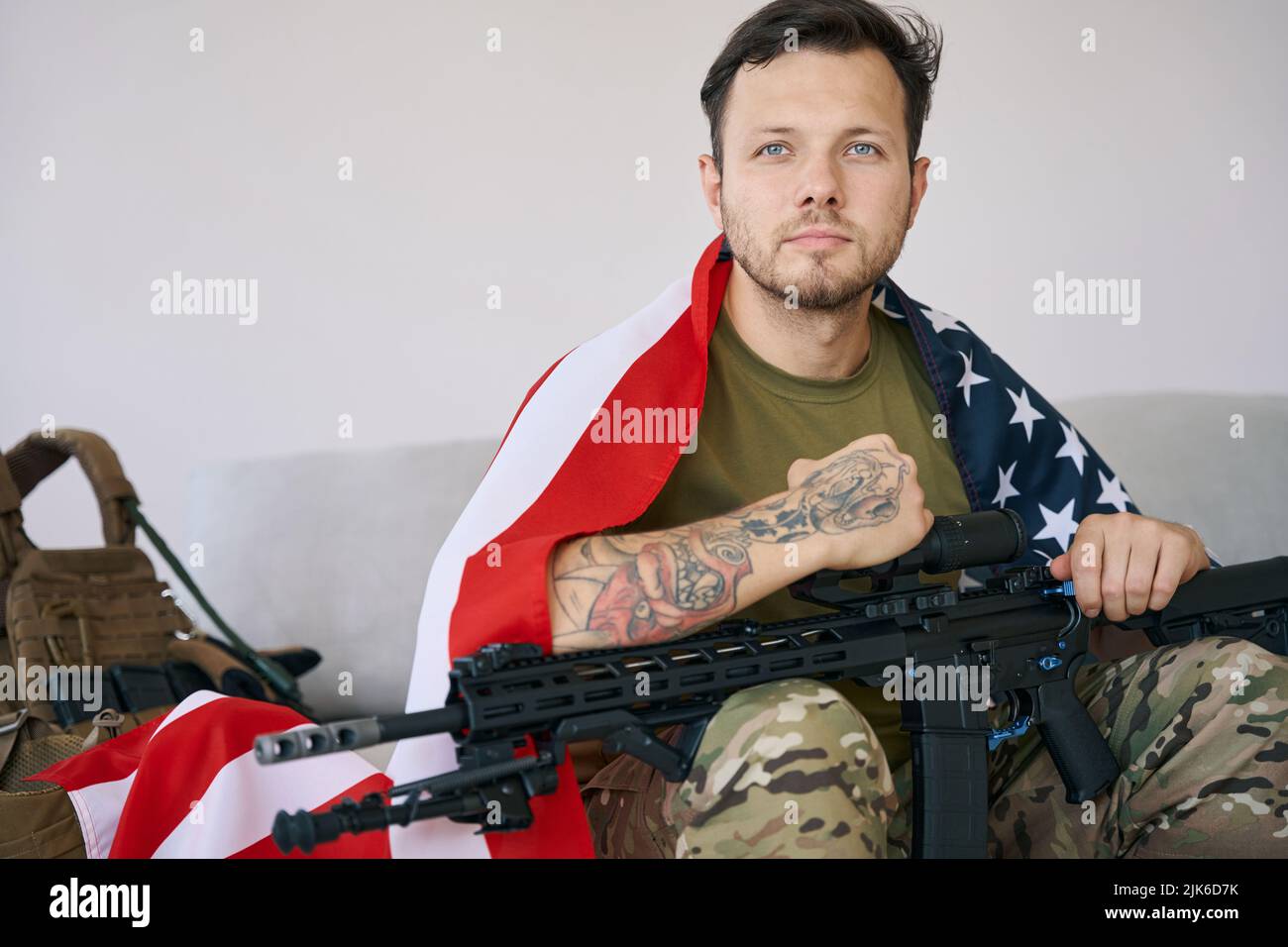 Confident soldier with American flag and rifle on couch Stock Photo - Alamy