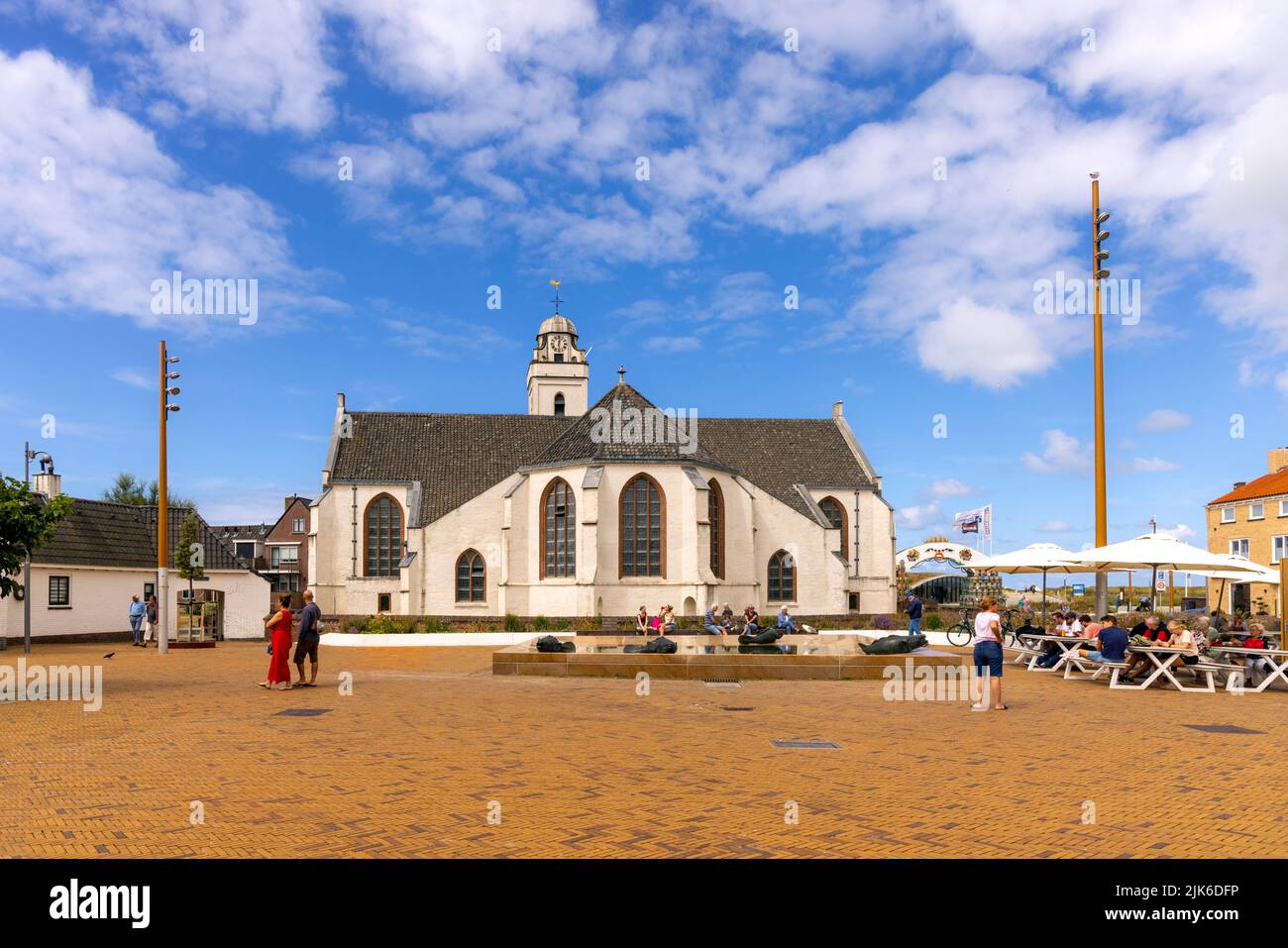 Relaxing tourists with view of Andreaskerk (Andrew's Church), a 15th century building and local landmark in Katwijk, South Holland, The Netherlands. Stock Photo