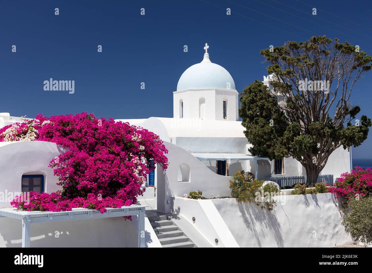 Picturesque whitewashed church, holiday accommodation with bright flowering bougainvillea, Aghios Artemios Traditional Houses, Santorini, Greece, EU Stock Photo