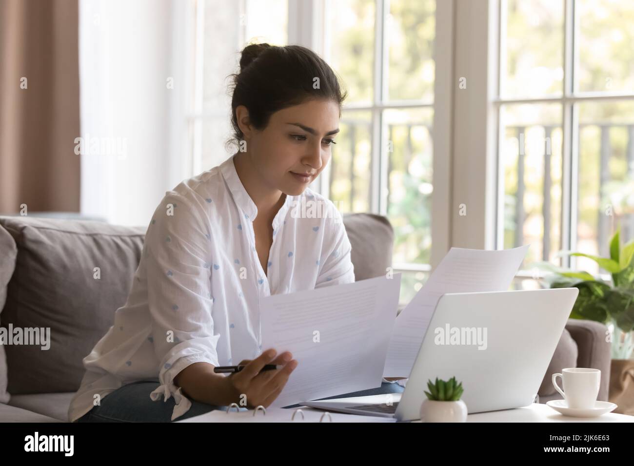 Serious Indian freelance business woman doing paperwork at home Stock Photo