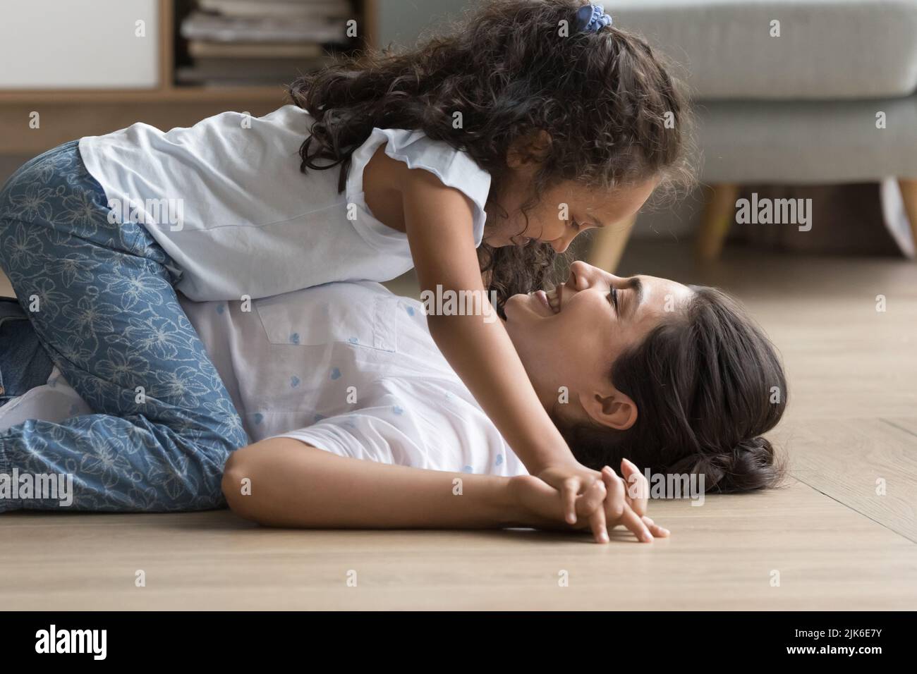 Happy little Indian kid girl resting on laughing mom Stock Photo