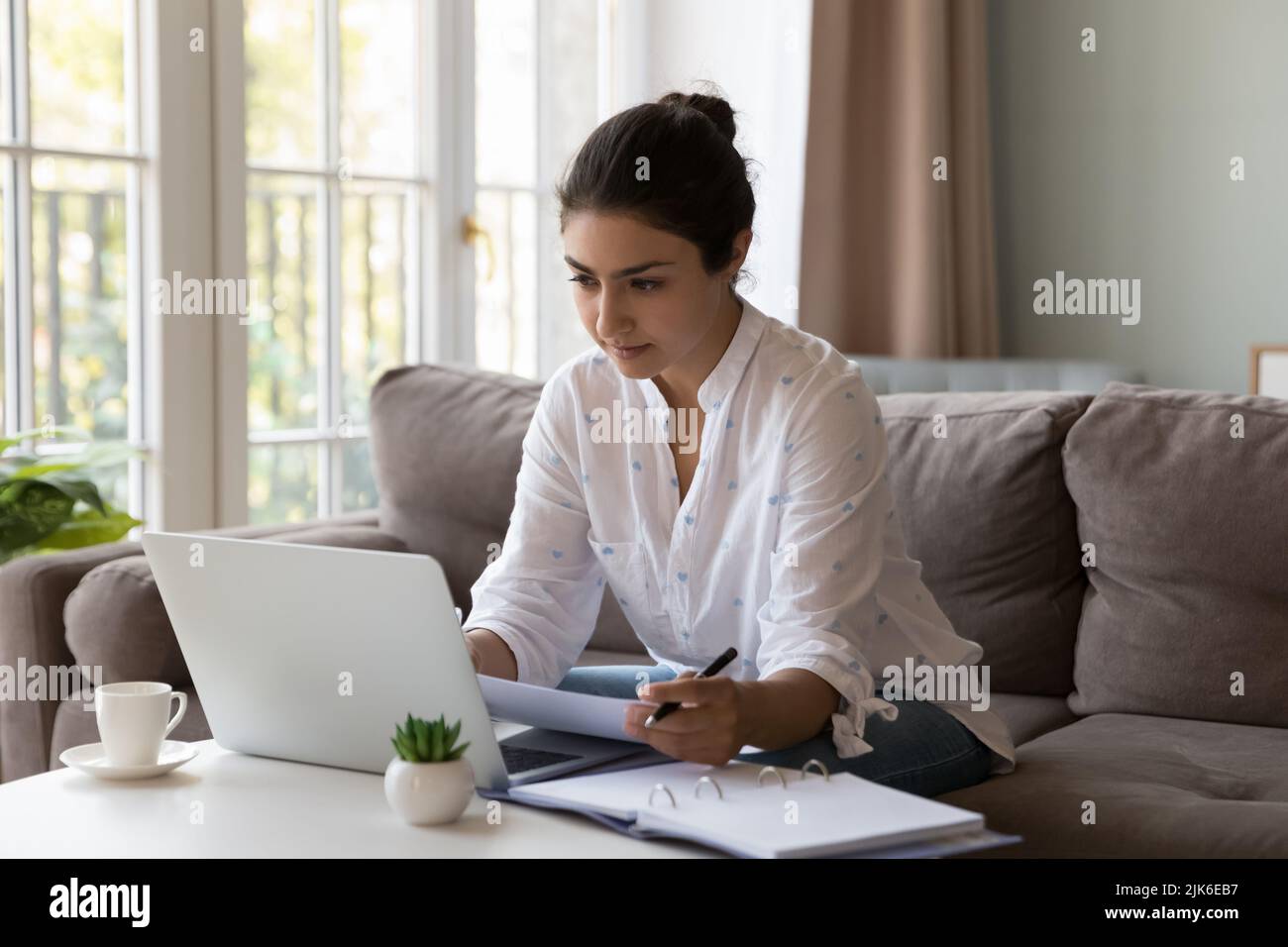 Focused Indian homeowner girl doing domestic paperwork at home Stock Photo