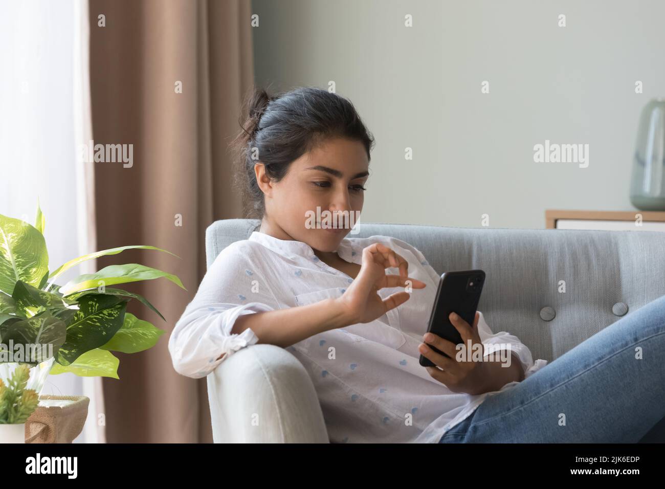 Thoughtful satisfied millennial Indian girl using online shopping app Stock Photo