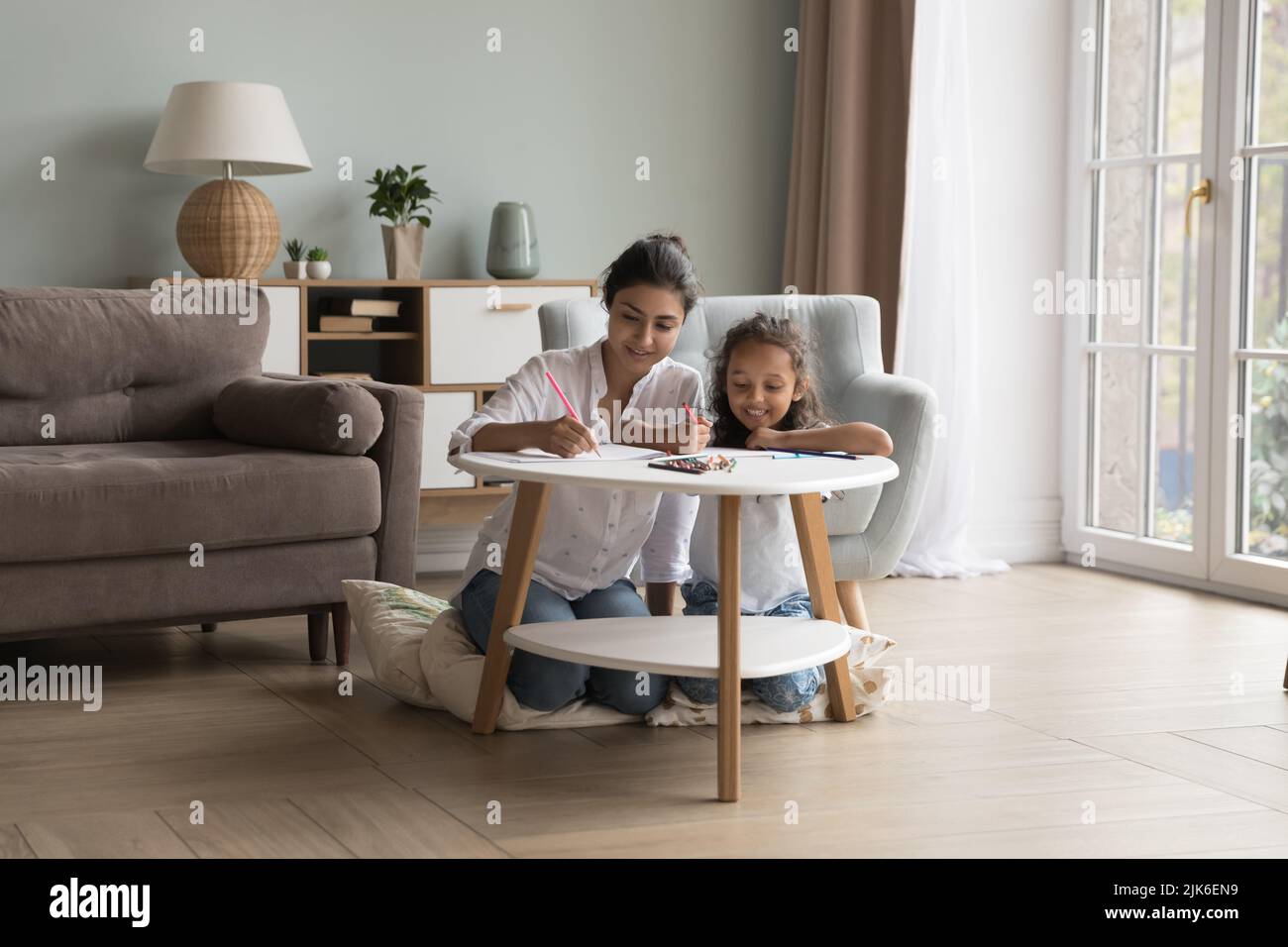 Engaged mother and happy little daughter kid drawing in pencils Stock Photo