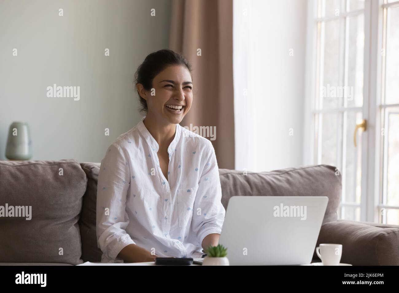 Cheerful happy Indian freelancer employee woman enjoying work from home Stock Photo