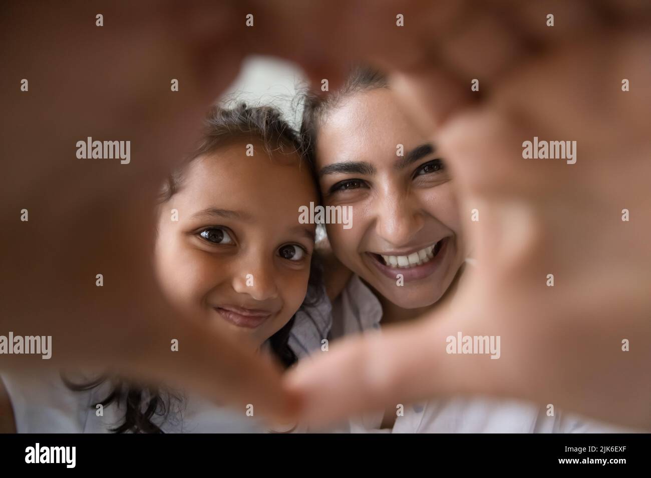 Happy kid girl and cheerful mom looking through hand heart Stock Photo