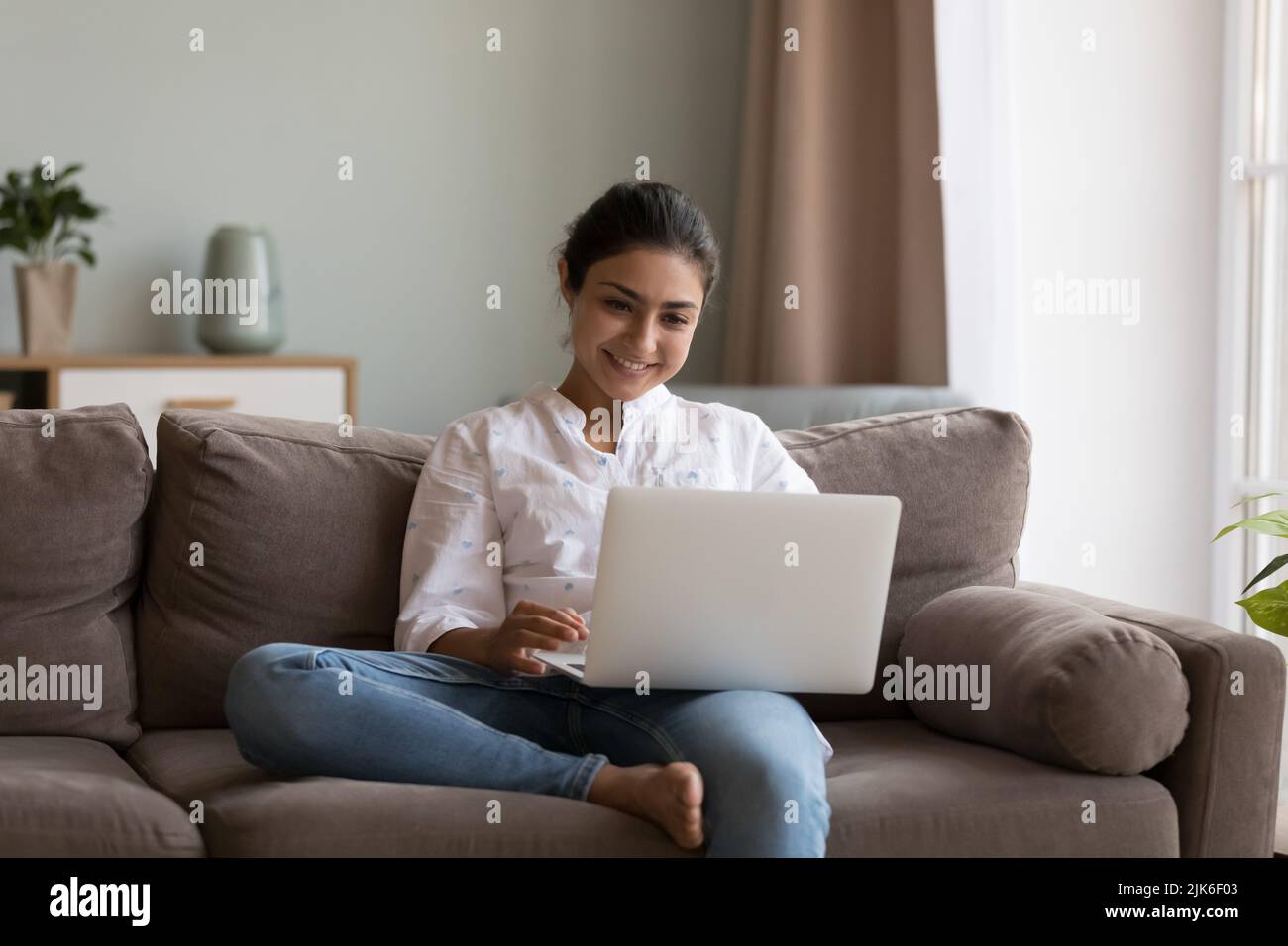 Cheerful young Indian freelance employee woman using online app Stock Photo