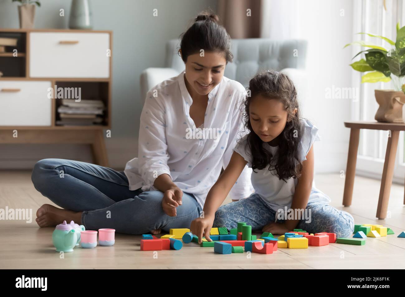 Cheerful mother and little daughter kid playing on heating floor Stock Photo