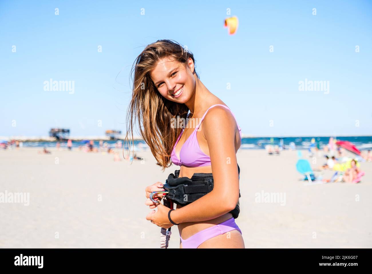 Beautiful kite surfing girl in pink bikini swimsuit adjusting her kite