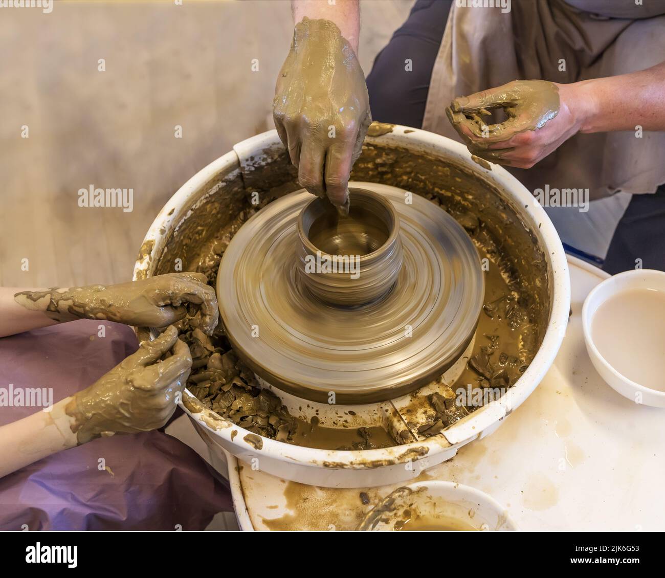 The Potter with student mold a pot from clay on a Potter's wheel ...