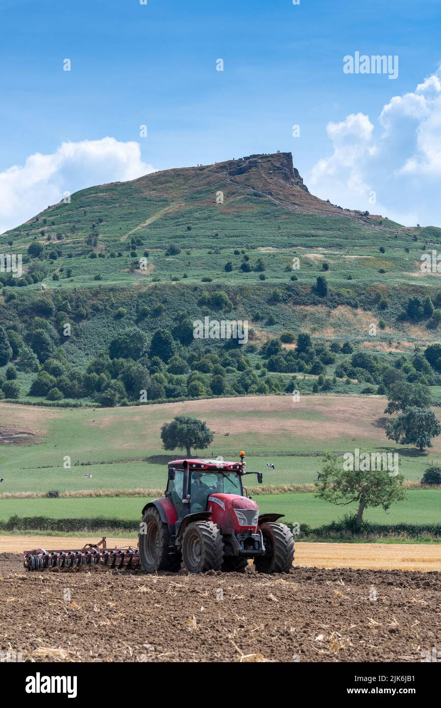 McCormick tractor Cultivating a seed bed on the edge of the North York Moors, with Roseberry topping in the background. Yorkshire, UK. Stock Photo