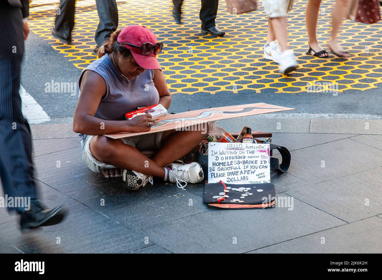 Homeless Indigenous Australian artist sitting cross legged on the pavement making paintings on the corner of Market and George Streets in Sydney. She was selling her art for $50 a piece. Stock Photo