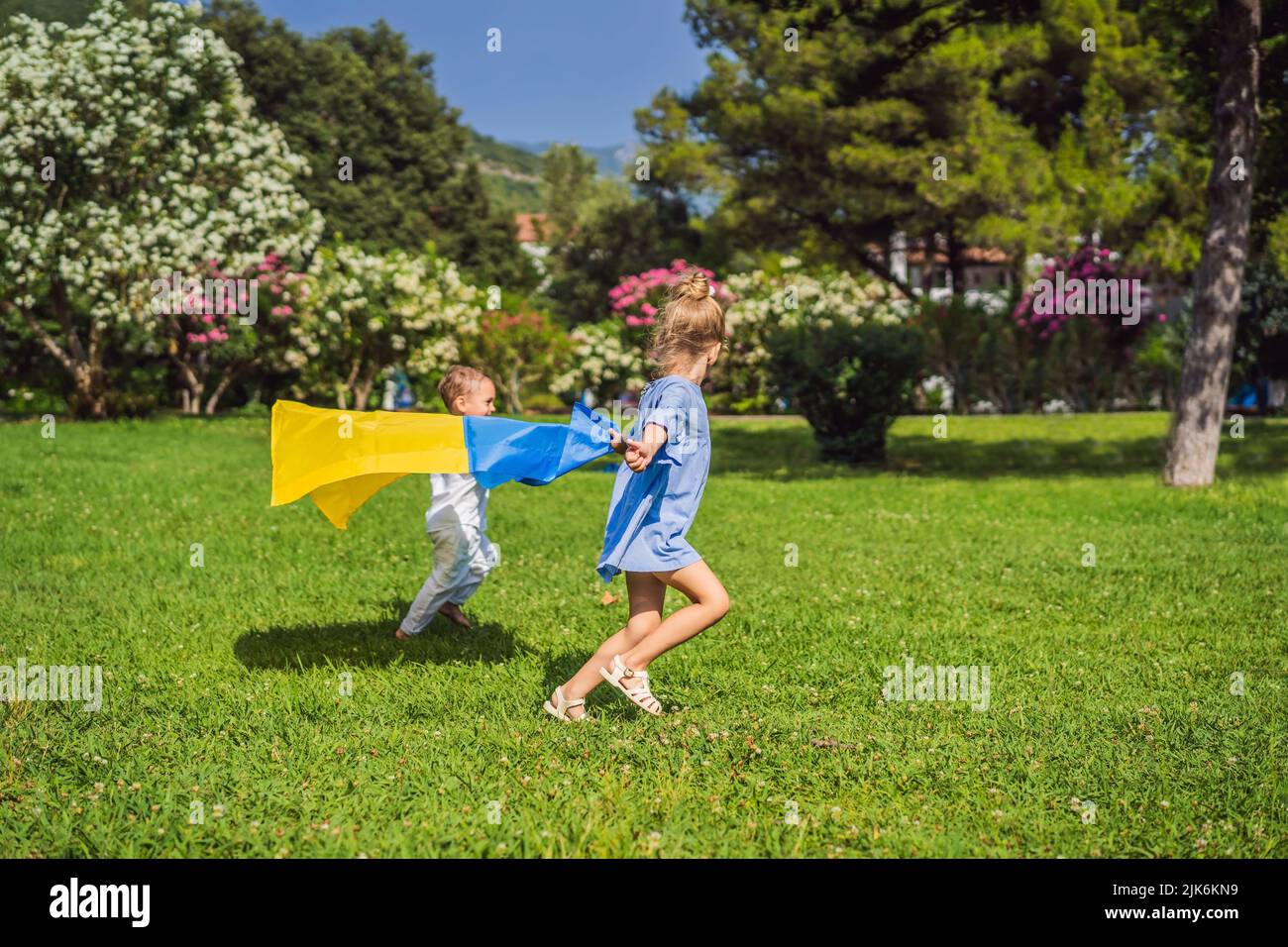 Ukrainian children with flag of Ukraine. Outside. Concept of problem of war in Europe, supporting of families and children, migrants, emigration Stock Photo