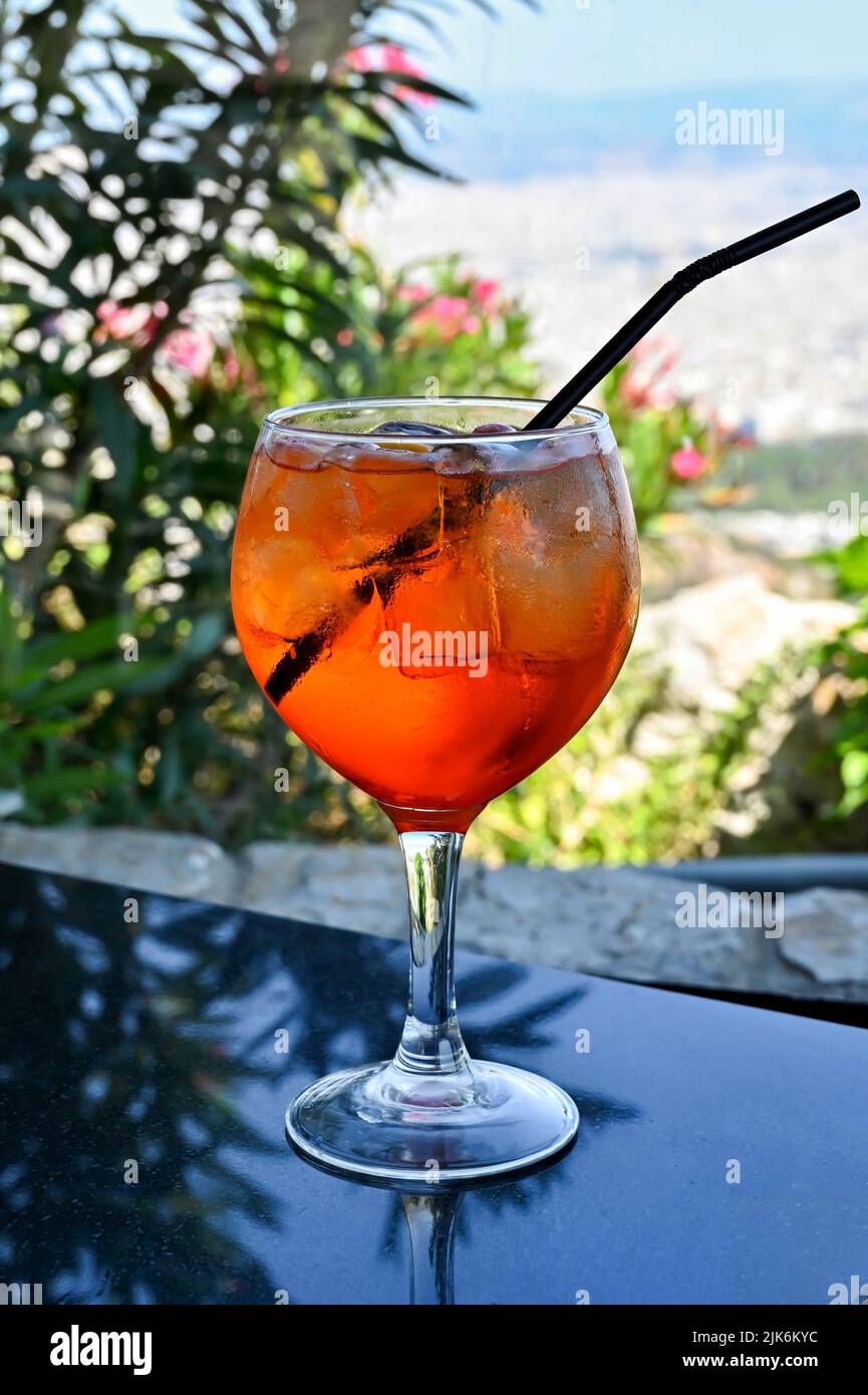 Large glass of Aperol Spritz drink with ice and a straw in a mountain top bar. No people. Stock Photo