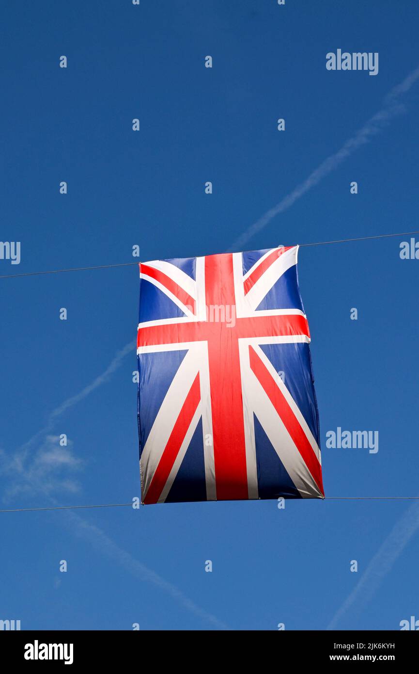 Union Jack flag hanging over a street against a deep blue sky. No people. Copy space. Stock Photo