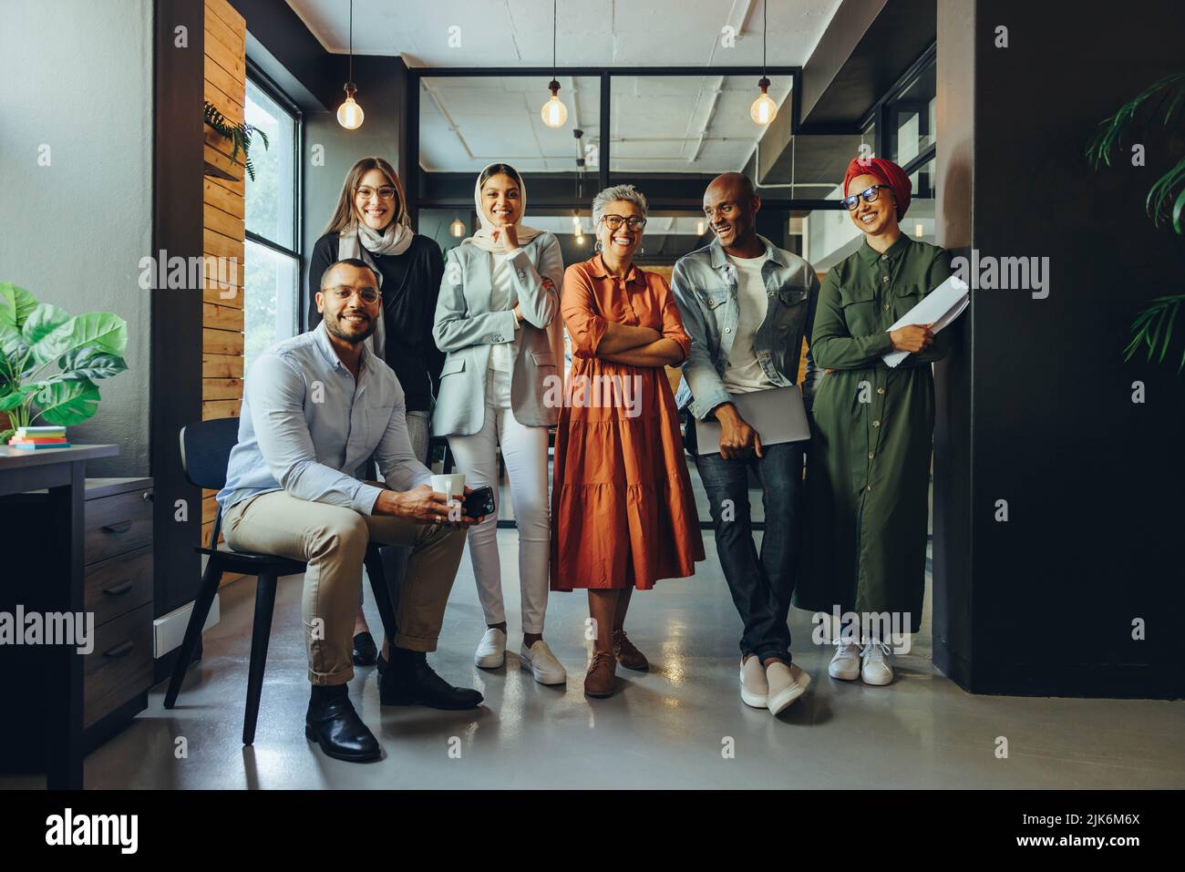 Successful business professionals smiling cheerfully in a modern office. Group of multicultural businesspeople running a creative startup in an inclus Stock Photo