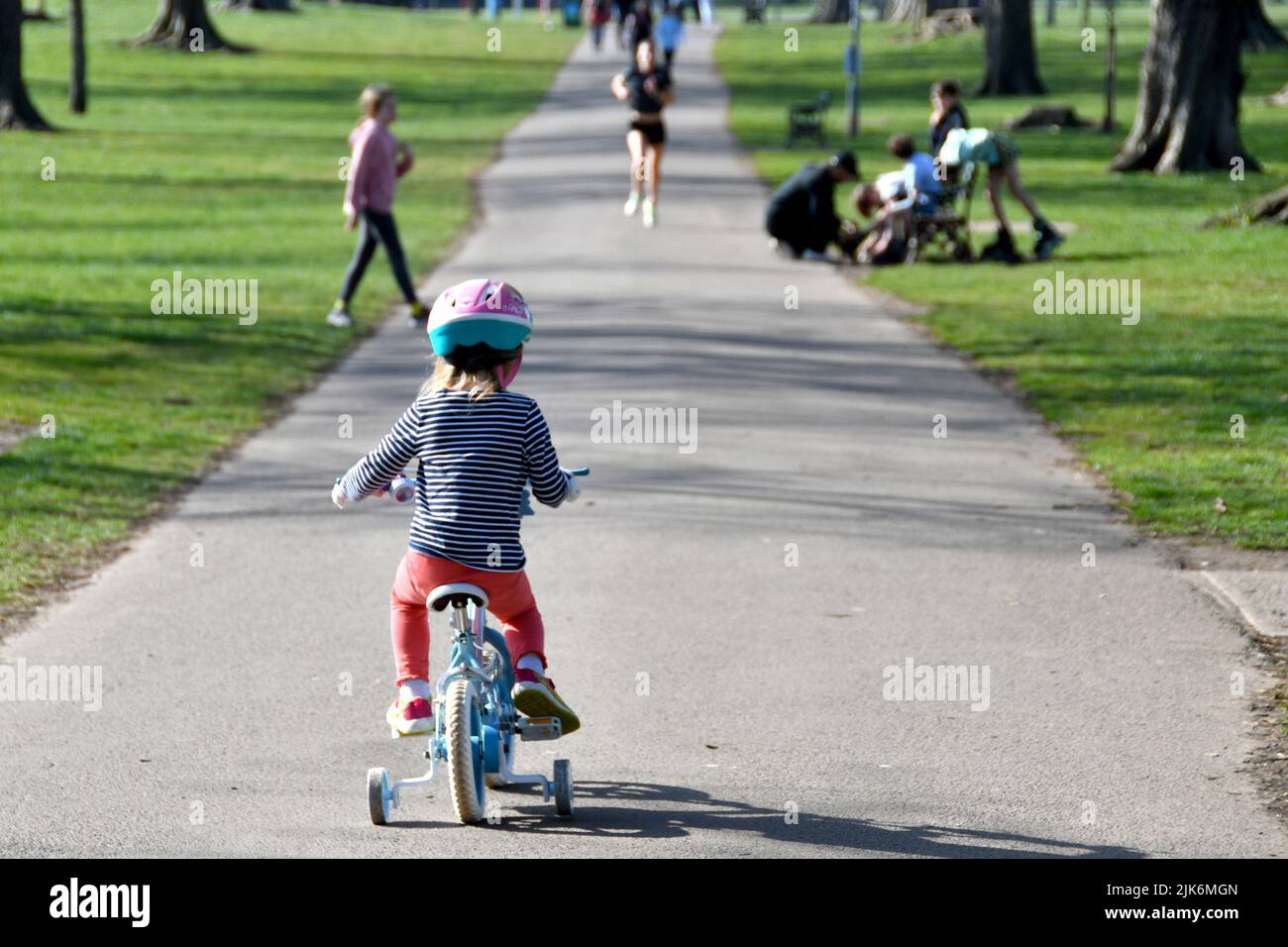 Cardiff, Wales - march 2022: Young child riding a small bicycle with stablisers through a public park Stock Photo